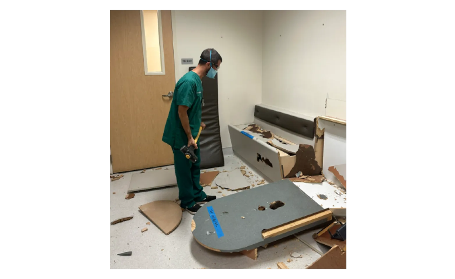 A staff member from Campbell holding a sledgehammer to a room in the hospital